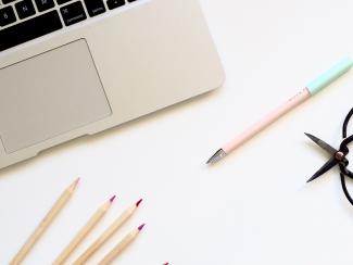 Laptop, pencils, and a scissor on a white table.